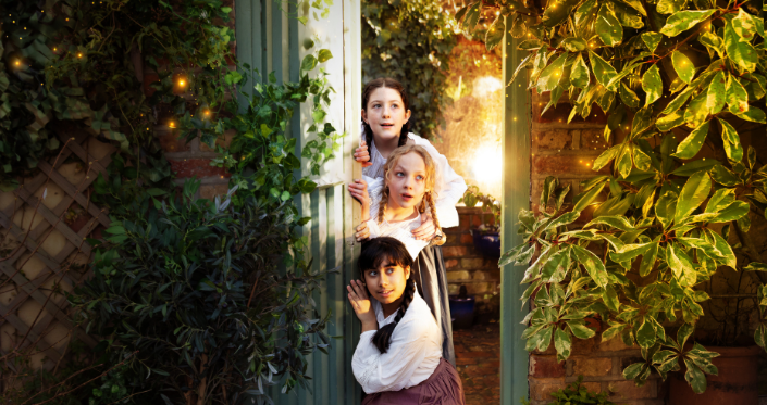 A weather-beaten wooden door in an ancient stone wall covered in ivy, is open slightly to reveal a glimpse of a lush green garden with magical sunlight pouring through